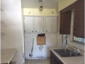 The kitchen before renovation, with dated wall cabinets, laminate counters and a stained ceiling.