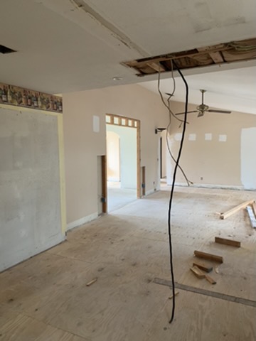 The same interior with a new plywood subfloor laid across the whole span, walls opened and the ceiling stripped back.